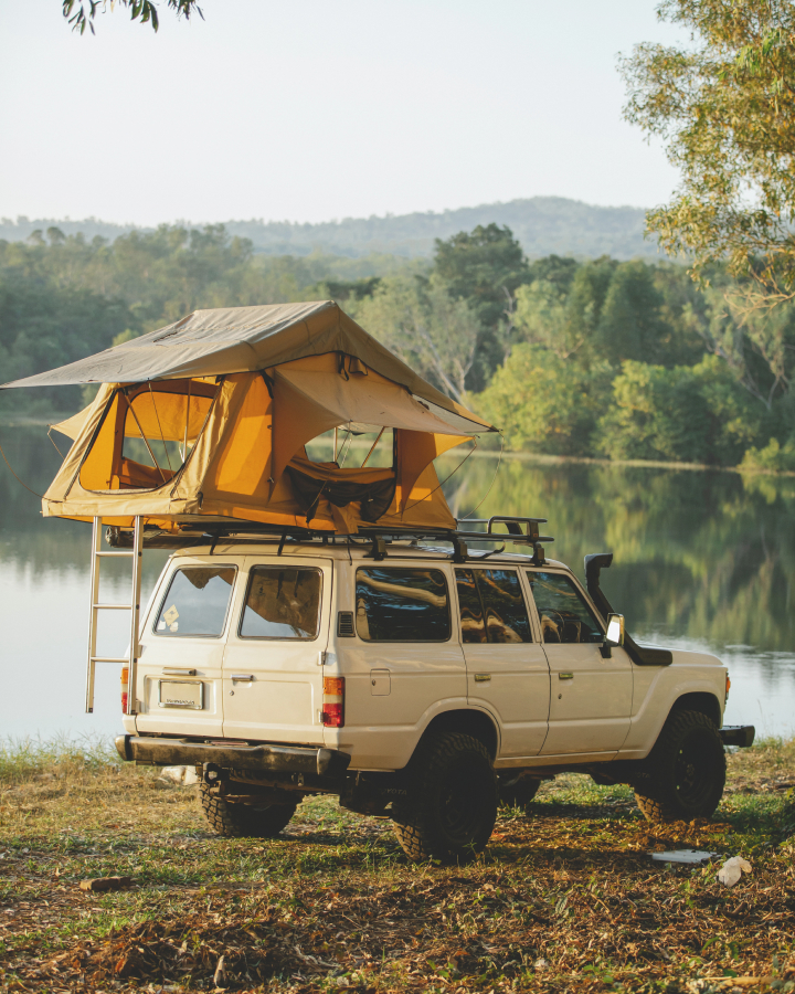 Imagem de um carro perto de uma lagoa em um camping.